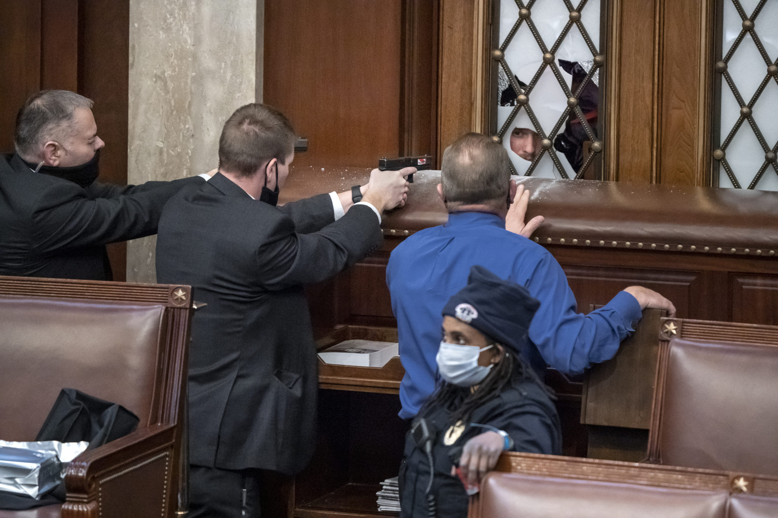 FILE - U.S. Capitol Police agents aim their guns as a pro-Trump mob tries to break into the House of Representatives chamber trying to stop the certification of President-elect Joe Biden's electoral college win, at the Capitol in Washington, Wednesday, Jan. 6, 2021. Rep. Troy Nehls, R-Texas, in blue shirt, talks to one of the rioters. (AP Photo/J. Scott Applewhite, FILE)