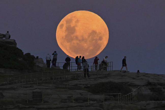 SYDNEY, AUSTRALIA - MAY 26: People watch the "Super Flower Blood Moon" rises over the Pacific Ocean at Bondi Beach in Sydney, Australia on May 26, 2021. The "Super" moon observed in May is often defined as "flower moon" as well, mainly due to association with flowers blooming at this time of year. During the eclipse, the moon turns into a deep blood-red color, known as "blood moon." This celestial incident -- known as "Super Flower Blood Moon" -- is the only full lunar eclipse of this year. (Photo by Steven Saphore/Anadolu Agency via Getty Images)