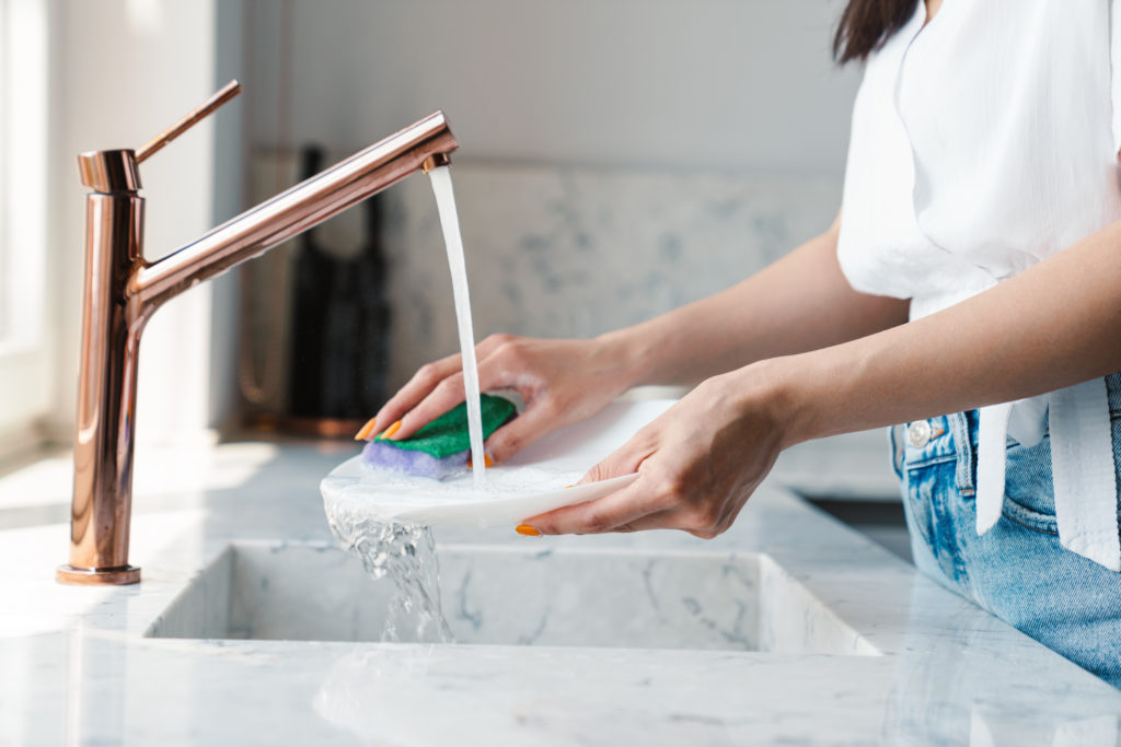Cropped photo of a young woman at home washing the dishes