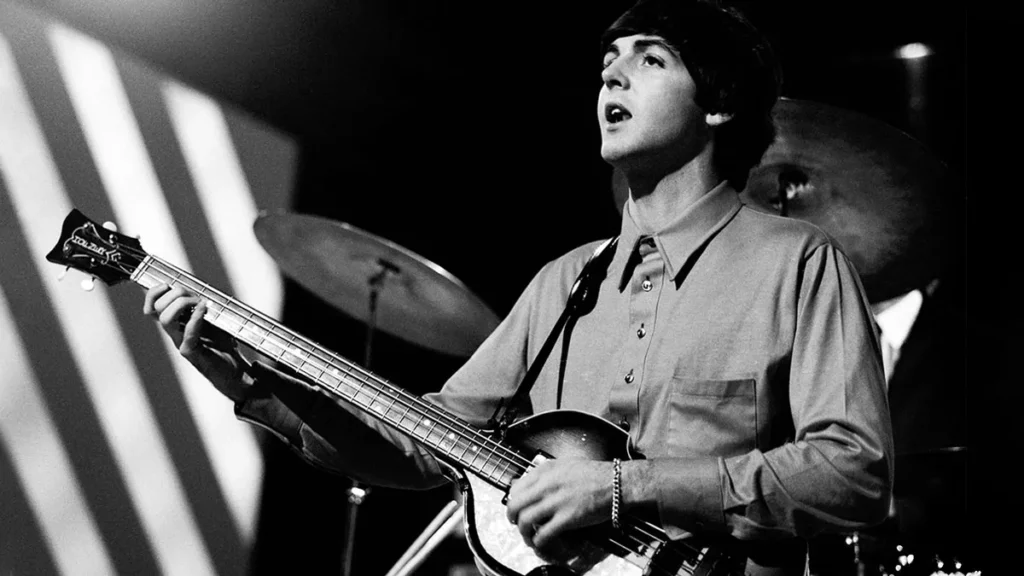 Old black and white photo of Paul McCartney with a Hofner guitar