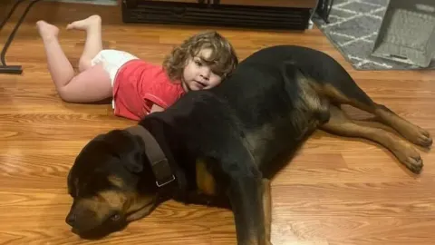 Toddler leans on dog